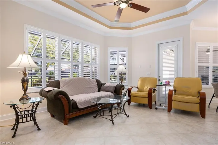 Living area with crown molding, a tray ceiling, and ceiling fan