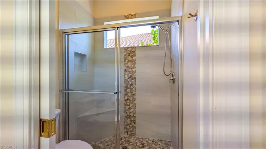 Full bathroom featuring a stall shower and toilet