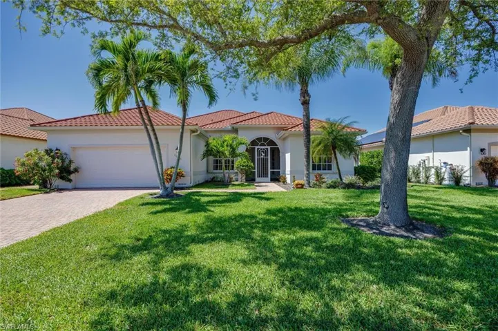 Mediterranean / spanish home featuring an attached garage, a front lawn, stucco siding, and driveway
