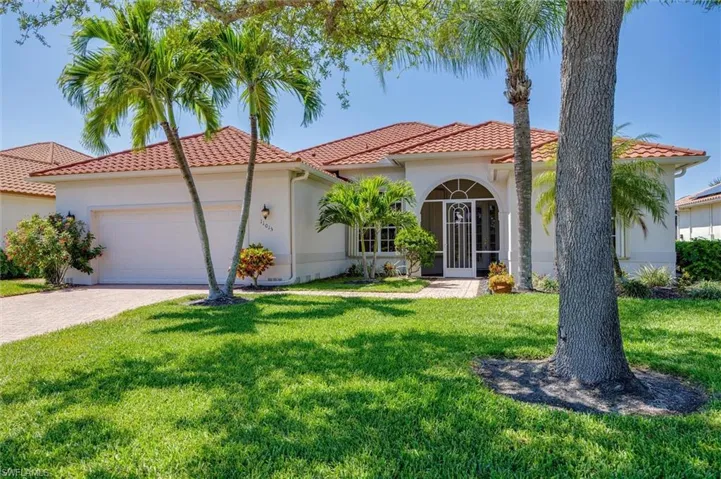 Mediterranean / spanish house with a garage, driveway, stucco siding, and a front yard