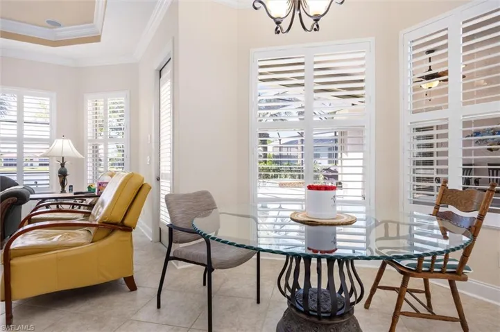 Dining space featuring ornamental molding, light tile patterned flooring, suspended lighting, and a raised ceiling
