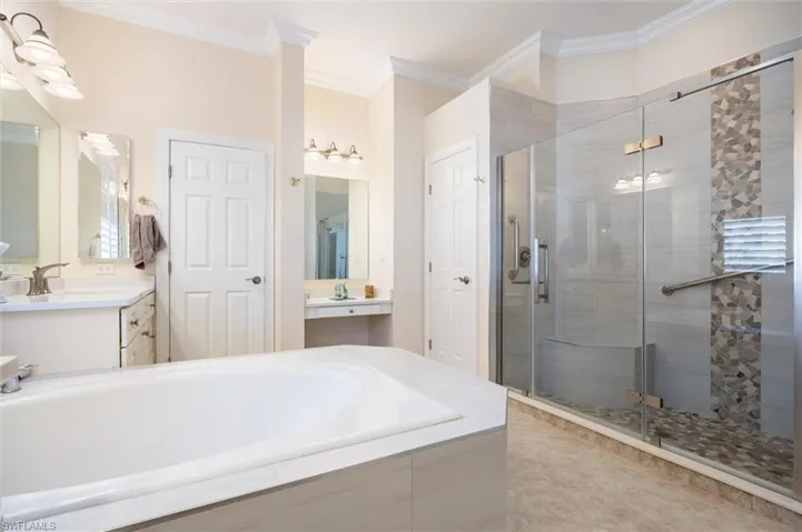 Bathroom featuring two vanities, a stall shower, ornamental molding, and a bath