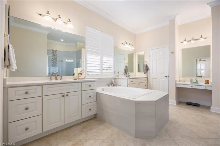 Full bathroom with two vanities, a stall shower, ornamental molding, light tile patterned flooring, and a bath