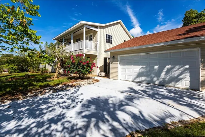 Traditional-style home with driveway, a balcony, an attached garage, and a shingled roof