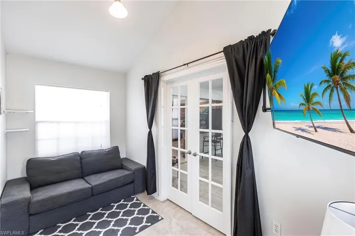 Tiled living room with french doors and lofted ceiling