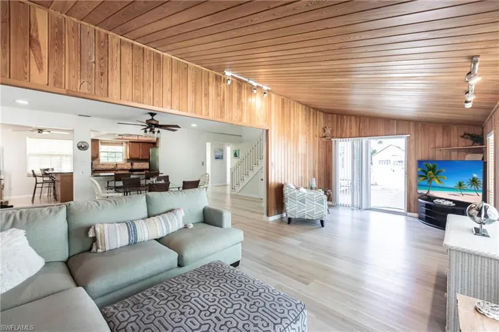 Living room with plenty of natural light, light wood-type flooring, wood ceiling, stairway, and lofted ceiling