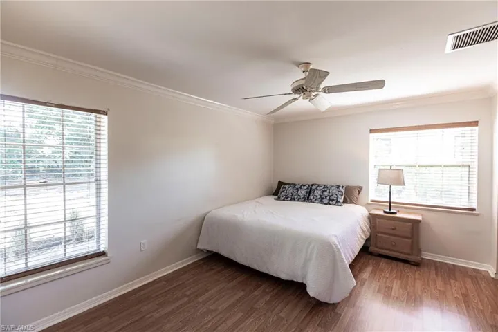Bedroom featuring ornamental molding, wood finished floors, and a ceiling fan