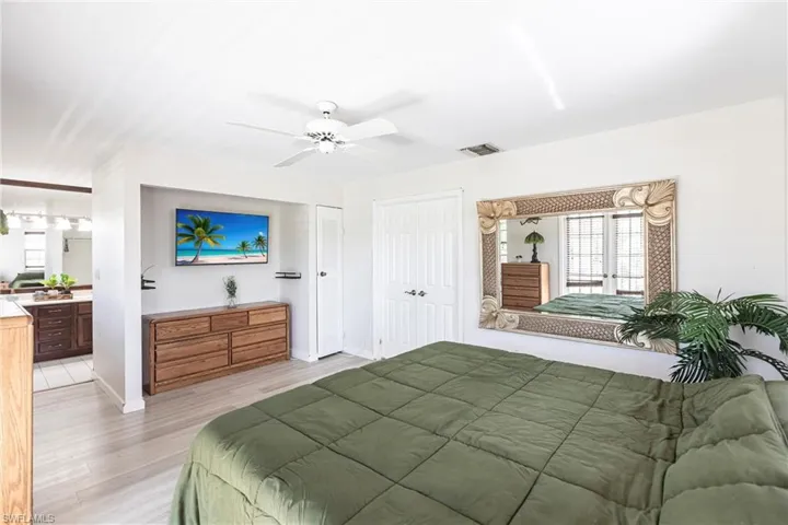 Bedroom with light wood-style flooring, a ceiling fan, and ensuite bathroom