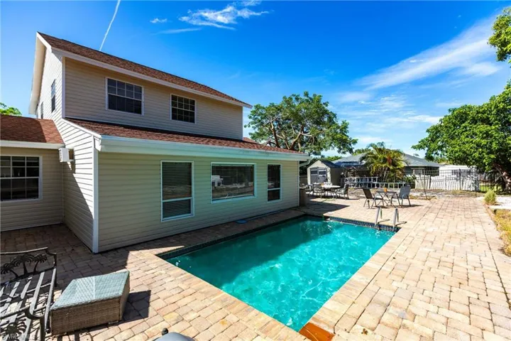 Rear view of property featuring a patio area and roof with shingles