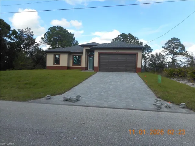 Prairie-style home with a front yard, decorative driveway, stucco siding, and an attached garage