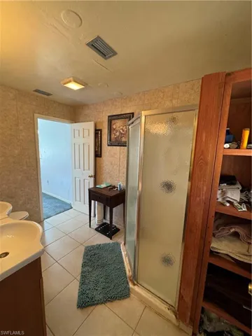 Bathroom with walk in shower, tile patterned flooring, and vanity