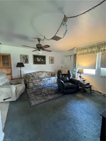 Carpeted living room featuring ceiling fan