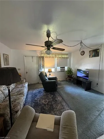 Living room with carpet flooring and ceiling fan