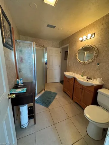 Bathroom with tile walls, tile patterned flooring, walk in shower, and vanity