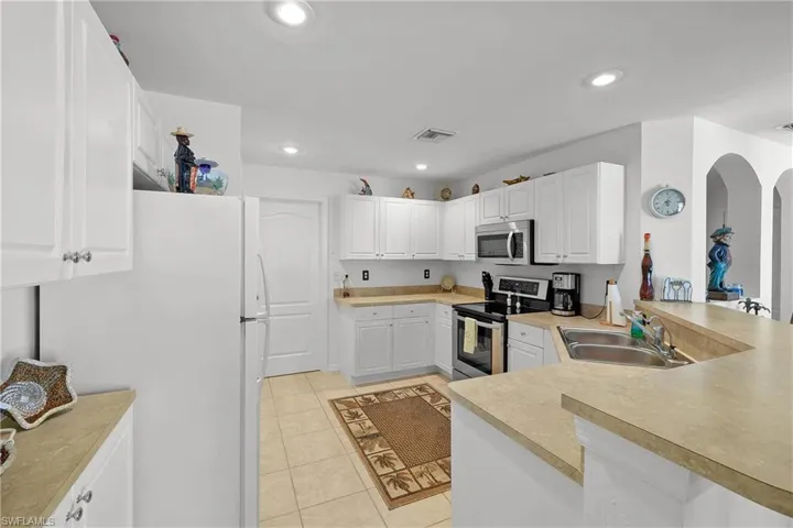 Kitchen featuring sink, kitchen peninsula, light tile floors, and appliances with stainless steel finishes