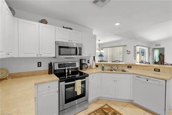 Kitchen with appliances with stainless steel finishes, white cabinetry, sink, and light tile floors