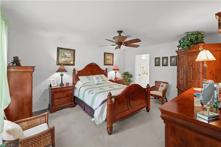 Carpeted bedroom with ceiling fan and ensuite bath