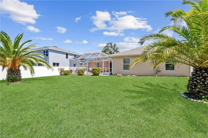 Back of house featuring a lawn and a lanai