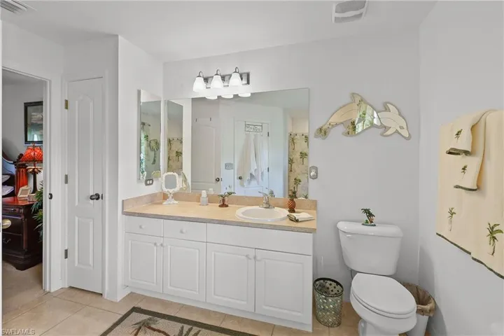 Bathroom with tile floors, dual bowl vanity, and toilet