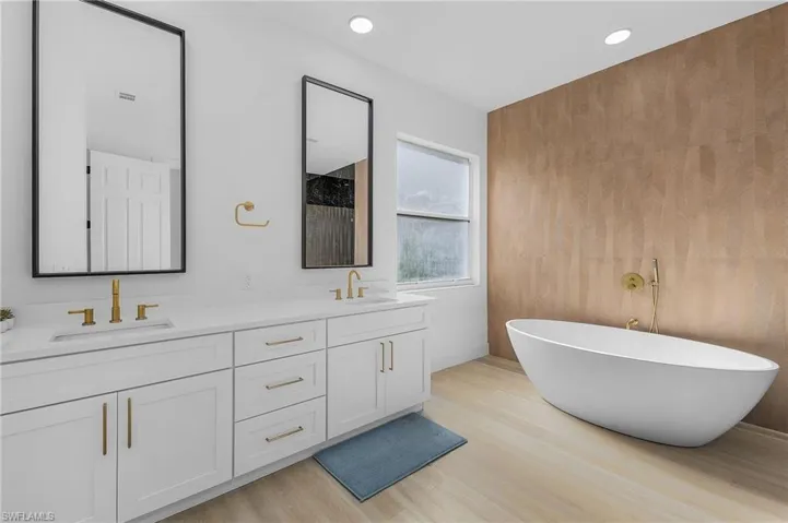 Primary Bathroom featuring hardwood / wood-style floors, vanity, and a tub