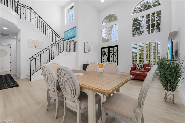 Dining space with a towering ceiling and light hardwood / wood-style floors
