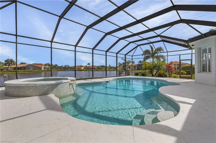 View of pool featuring a large lanai with lake  view, an in ground hot tub, and a patio