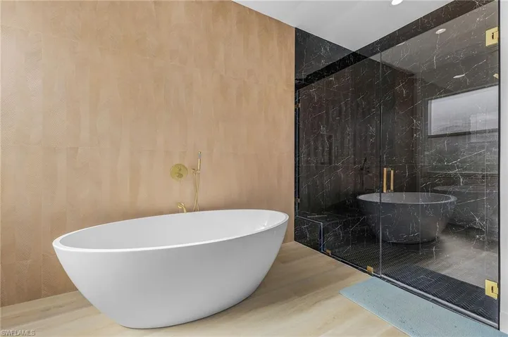 Primary Bathroom featuring hardwood / wood-style floors, plus walk in shower, and tile walls