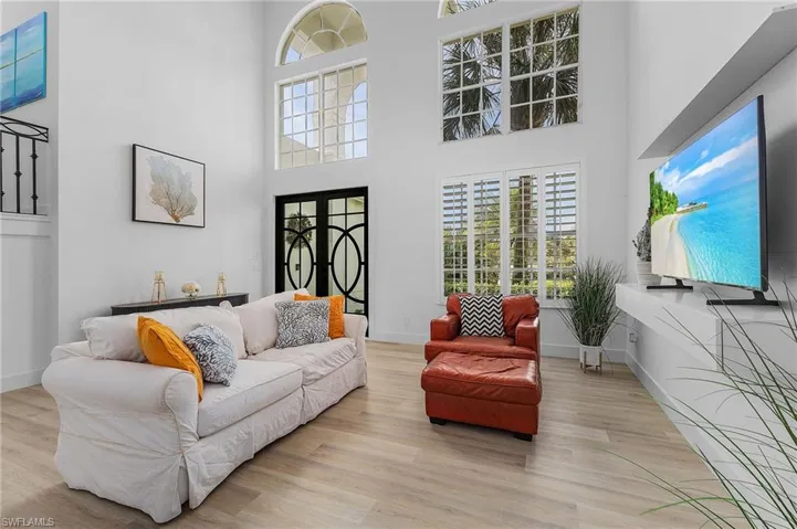 Living room with light wood-type flooring and a high ceiling
