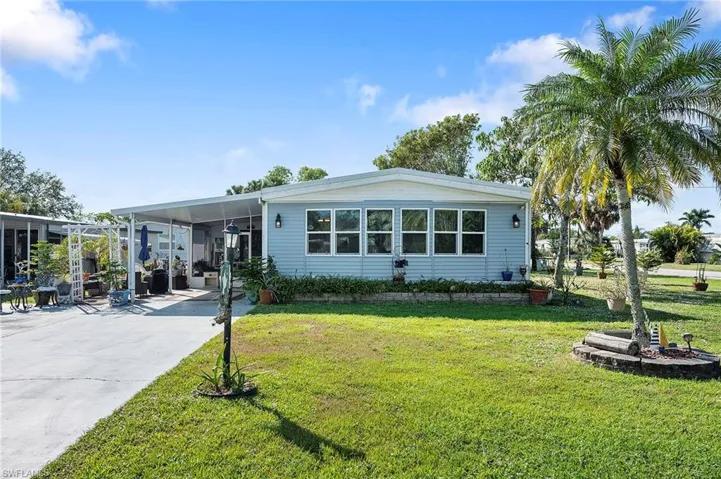 Manufactured / mobile home featuring a front yard and a carport
