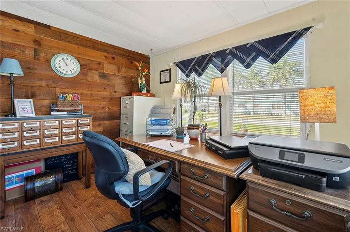 Office with wood-type flooring and wooden walls