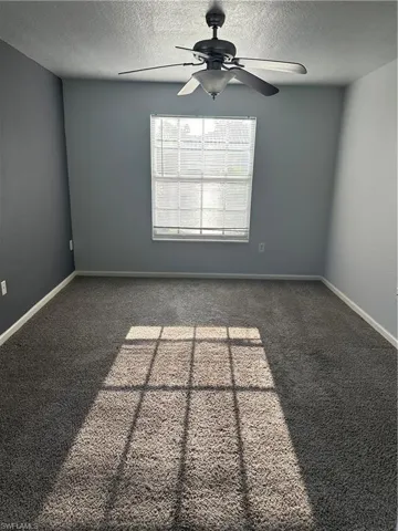 Wall-to-wall carpet flooring, ceiling fan, and window with blinds