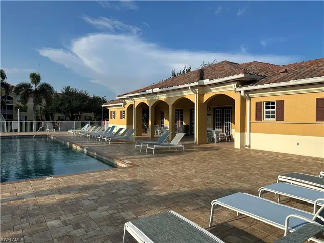 Poolside building with arched portico, tile roof, and shuttered windows