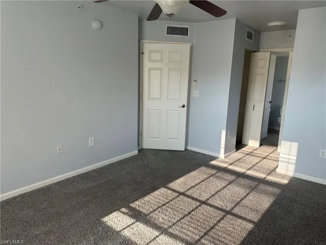 Plush carpet flooring, light blue wall paint, ceiling fan, white paneled doors, and an overhead light fixture