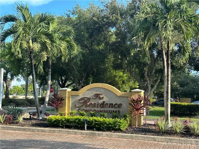Entry monument with "The Residence Condominiums" inscription, framed by tropical landscaping