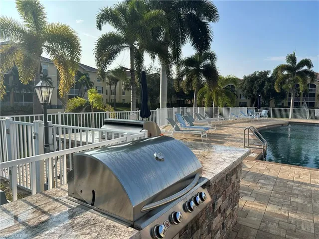 Outdoor kitchen featuring a built-in stainless steel grill and stone-clad base, stone-finish countertop, and paver patio