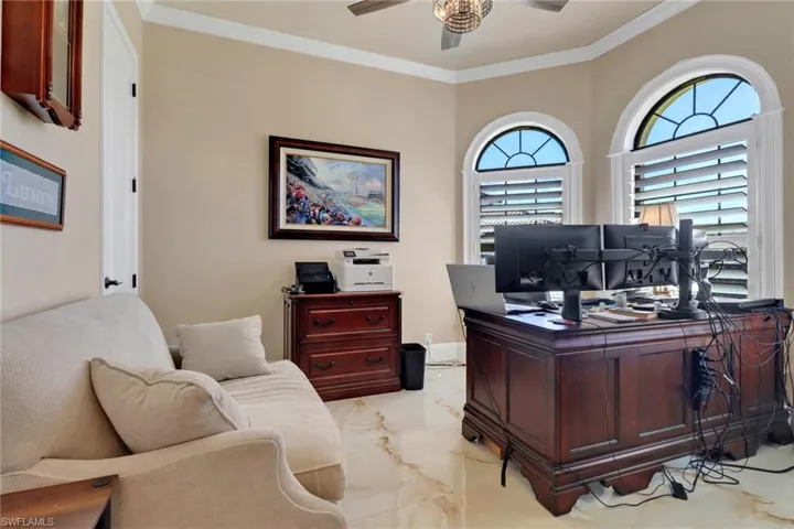 Home office featuring ceiling fan, light marble finish flooring, and crown molding