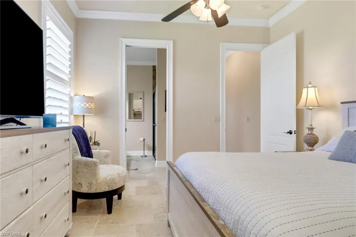 Bedroom featuring crown molding, light stone finish flooring, and a ceiling fan