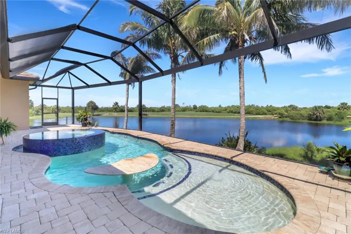 View of swimming pool with a pool with connected hot tub, a patio, glass enclosure, and a water view