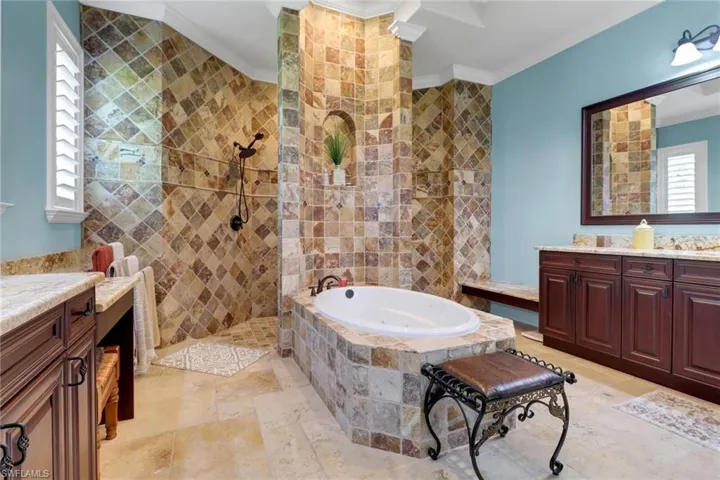 Full bathroom featuring vanity, a garden tub, crown molding, stone tile floors, and walk in shower