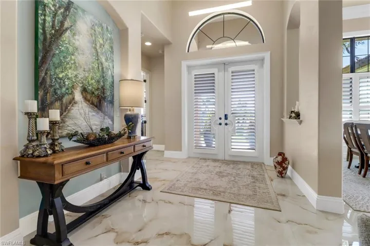 Foyer entrance featuring french doors, marble tiled floors, and arched walkways