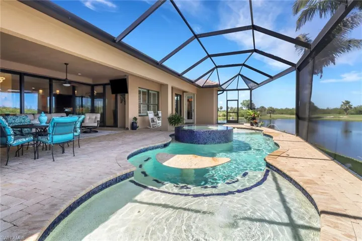 View of swimming pool with a patio area, a pool with connected hot tub, ceiling fan, and glass enclosure