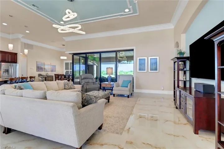 Living room with light marble finish flooring, ornamental molding, a chandelier, and recessed lighting