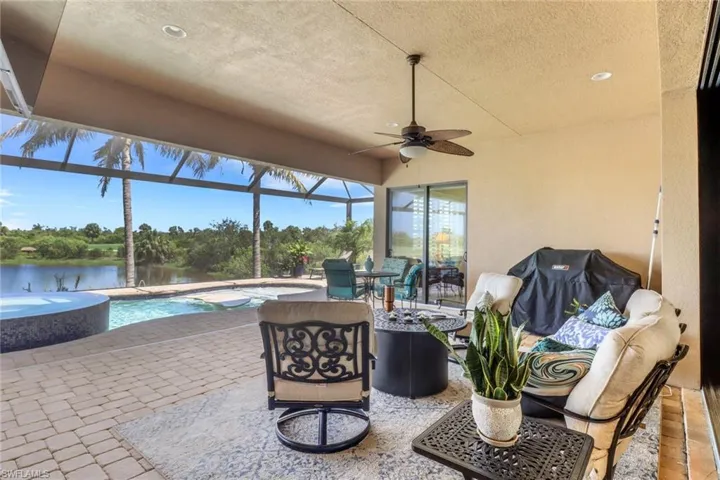 View of patio with a hot tub, an outdoor pool, ceiling fan, a lanai, and a water view