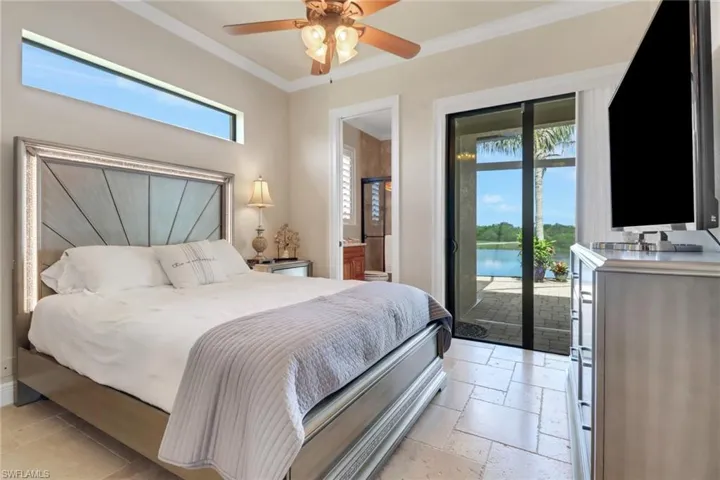 Bedroom featuring stone tile floors, access to outside, ornamental molding, ensuite bath, and ceiling fan