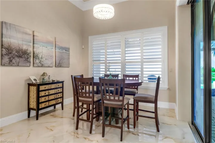 Dining room featuring marble tiled floors, a chandelier, and crown molding