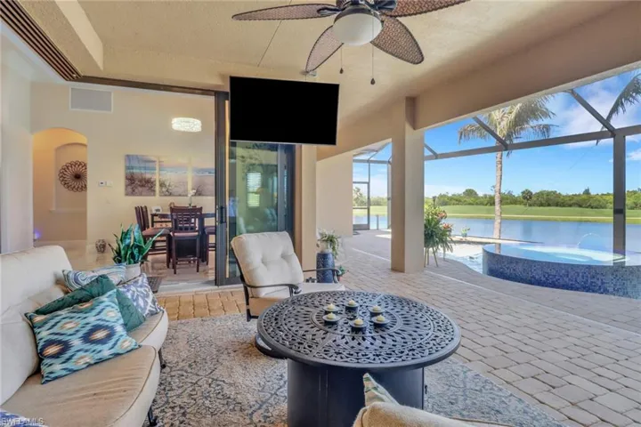 View of patio featuring ceiling fan, a pool with connected hot tub, an outdoor living space, and glass enclosure