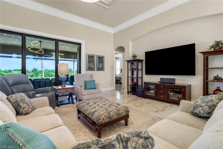 Living room with arched walkways, crown molding, and marble tiled flooring
