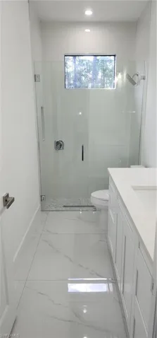 Hall bathroom featuring a shower with door, vanity, and toilet