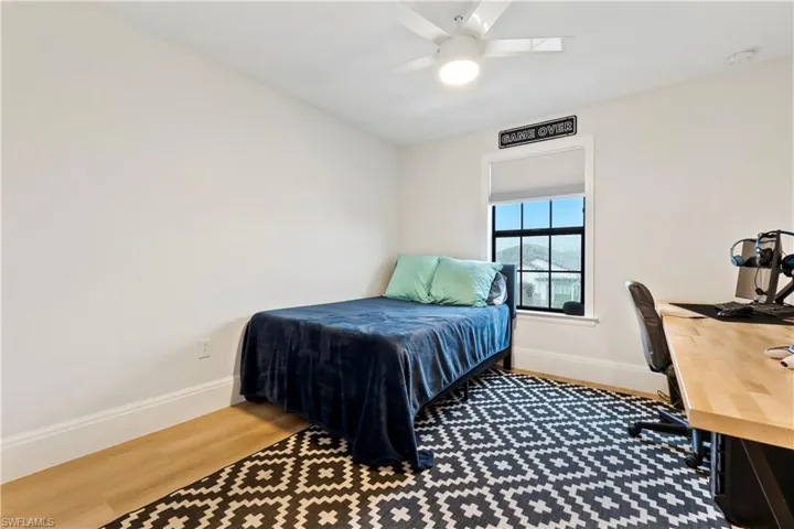 Bedroom featuring wood finished floors, a ceiling fan, and a desk