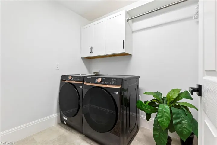 Laundry room featuring washing machine and dryer, cabinet space, and light tile patterned flooring